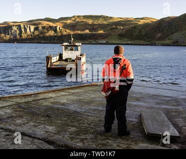 Männer tragen Arbeitskleidung stehen auf dem Pier mit einem Das Boot fährt ab Stockfoto