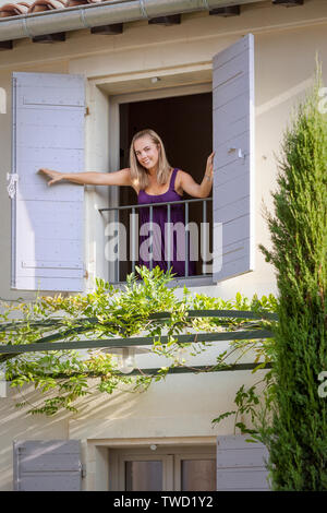 Junge Frau auf der Suche Fenster der klassischen provenzalischen Haus in St. Remy de Provence, Frankreich Stockfoto