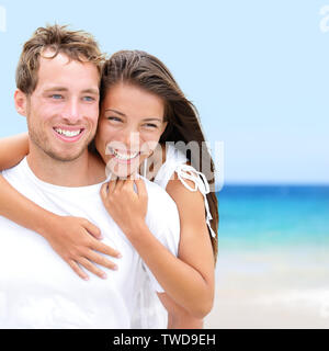 Strand paar Liebhaber auf romantischen Travel in Love auf Flitterwochen Urlaub Romantik. Junge Menschen glücklich, asiatische Frau und kaukasischen Mann umarmen im Freien auf tropischen Strand in Casual Wear.