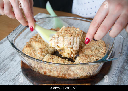 Weibliche Hände nehmen ein Stück Apfel knackig frisch gebackene hausgemachte Kuchen aus einem Glas Schimmel auf einem Teller, Copyspace Stockfoto