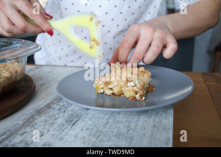 Weibliche Hände nehmen ein Stück Apfel knackig frisch gebackene hausgemachte Kuchen aus einem Glas Schimmel auf einem Teller, Copyspace Stockfoto