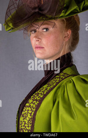 Späten viktorianischen Frau trug eine grüne Seide Ensemble und einem großen Hut Stockfoto