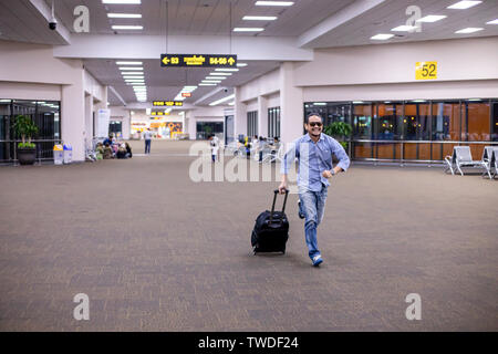 Asiatischer mann Reisende mit Koffern zu Fuß und Transport auf einem Flughafen Stockfoto
