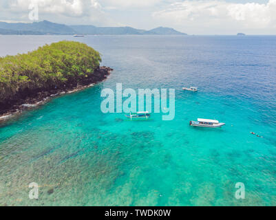 Meer Bucht mit türkisfarbenem Wasser und einem kleinen weißen Strand. Schöne Lagune und Insel vulkanischen Ursprungs mit dichtem Wald bedeckt, Ansicht von oben Stockfoto