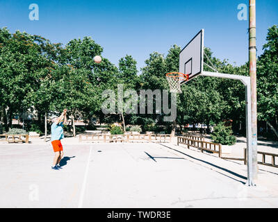 Alter Mann spielen und Coaching Warenkorb allein in einem Basketballplatz Stockfoto