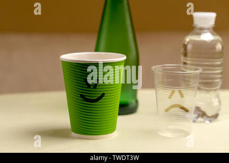 Glasflasche mit rein mineralischen Trinkwasser und einem pappbecher und ein Glas mit einer Kunststoffflasche Stockfoto