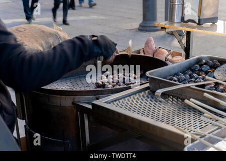 Einem Straßenhändler braten einige Kastanien in Lissabon, Portugal. Gebratene Kastanien sind eine beliebte billige Snack in Portugal. Stockfoto