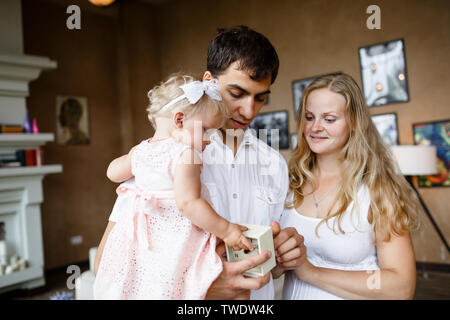 Zärtliche Umarmungen der Familie. Glücklich schwangere Mutter, Vater, Tochter genießen einander zu Hause Stockfoto
