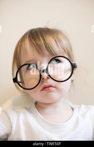 Schwere zwei Jahre altes Mädchen in großen schwarzen Brille auf der Nase closeup Stockfoto