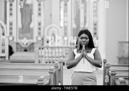 Afrikanische amerikanische Frau in der Kirche zu beten. Gläubige meditiert, in der Kathedrale und spirituelle Zeit des Gebets. Afro girl gefalteten Händen mit Rosenkranz. Stockfoto