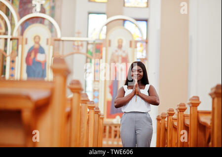 Afrikanische amerikanische Frau in der Kirche zu beten. Gläubige meditiert, in der Kathedrale und spirituelle Zeit des Gebets. Afro girl gefalteten Händen mit Rosenkranz. Stockfoto