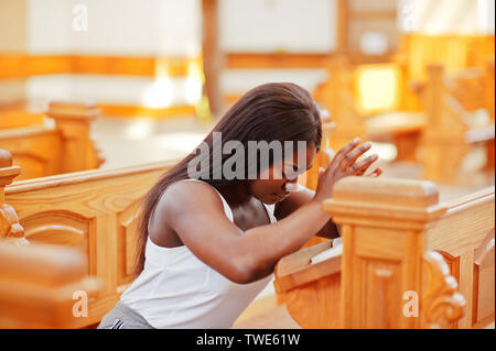 Afrikanische amerikanische Frau in der Kirche zu beten. Gläubige meditiert, in der Kathedrale und spirituelle Zeit des Gebets. Afro girl gefalteten Händen während der Sitzung Stockfoto