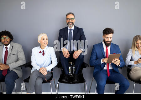 Porträt der Gruppe von verschiedenen Corporate Kollegen in einer Reihe stehen gemeinsam an einem Tisch in einem hellen, modernen Büro Stockfoto