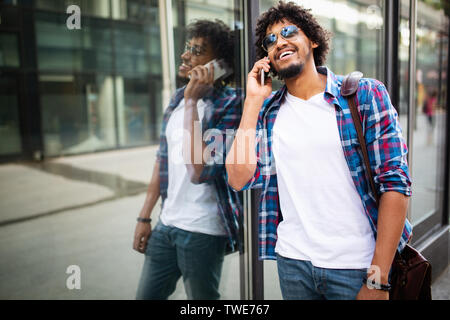 Close up Portrait von Lachen, schwarzen jungen Mann Gespräch am Handy und Wegsehen Stockfoto