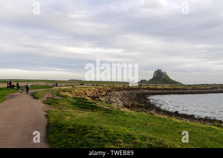 Besucher am Tag, einem Spaziergang in Richtung der 1550 erbaute Lindisfarne Castle auf der heiligen Insel in Northumberland, Großbritannien Stockfoto