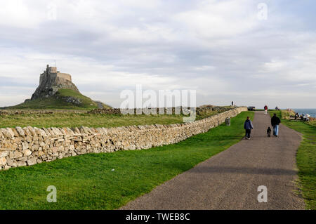 Die Besucher eines Tagesausflugs machen einen Spaziergang zum 1550 erbauten Lindisfarne Castle auf Holy Island in Northumberland, Großbritannien, die kleine Gezeiteninsel ist Stockfoto
