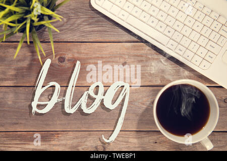 Blog Text mit Computer Tastatur, Tasse Kaffee und dem Blumentopf. Holztisch Hintergrund in Vintage getönt. Stockfoto