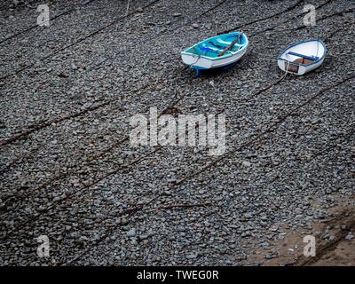 Zwei Ruderboote liegen oben auf Ketten auf einem Kieselstrand Stockfoto