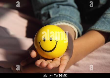 Mädchen hält einen Ball mit Smiley-Gesicht Stockfoto