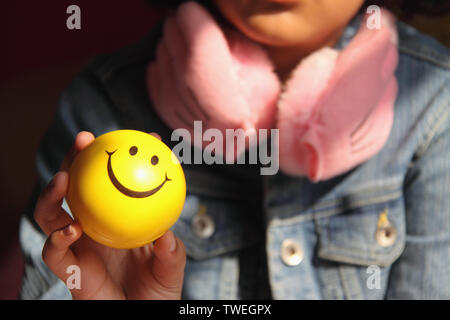 Mädchen hält einen Ball mit Smiley-Gesicht Stockfoto