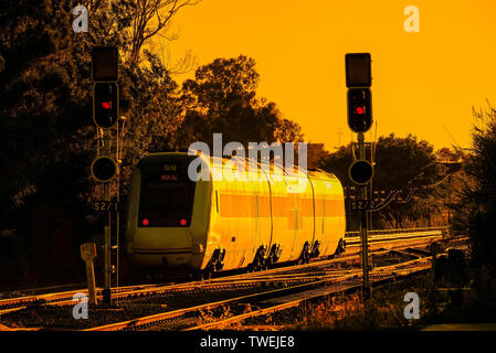 Zum Sonnenuntergang mit modernen Reisenden durch eine Station mit Ampel Zug Stockfoto