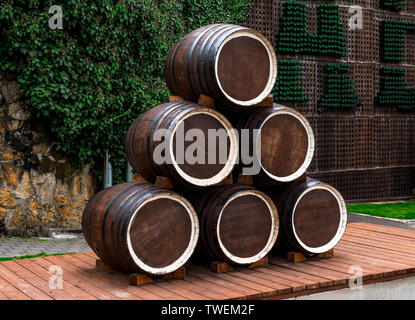 Weinbau und die Produktion von alkoholischen Getränken Konzept - hölzerne Weinfässer aus einer Pyramide auf eine Plattform des Boards, im Hintergrund ein Stein w Stockfoto