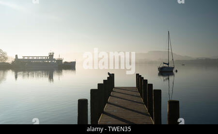 Schöne unplugged Landschaft Bild der Segelyacht sitzt immer noch in ruhigen See Wasser im Lake District während der friedlichen nebligen Herbst Sonnenaufgang Stockfoto