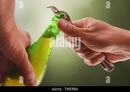 Das Öffnen einer Flasche aus grünem Glas mit einem Metall Flaschenöffner und grünen Hintergrund. Horizontale Komposition. Vorderansicht. Stockfoto