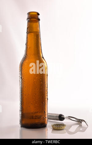 Bier Flasche gefüllt und öffnen auf Glas Tisch und weißen Hintergrund. Vertikale Komposition. Vorderansicht. Stockfoto