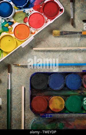 Box mit Wasserfarben und Pinsel auf einem Tisch. Stockfoto