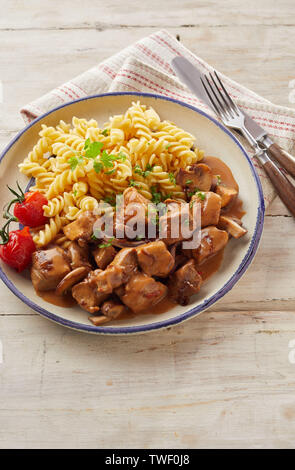 Ansicht von oben der Schüssel hält leckere Pasta und zart geschnittene Kalbsfiletwürfel über rustikale Holz Hintergrund Stockfoto