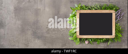 Kleine vintage Schiefer sowie eine Auswahl an frische Kräuter und essbare Blüten bilden einen Rahmen in einem breiten Panorama Banner mit cop Platz auf strukturierte umgeben Stockfoto