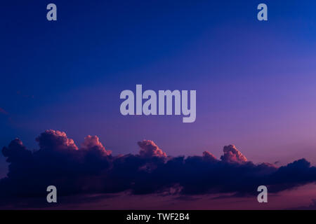 Abend Himmel bei Sonnenuntergang Hintergrund. Dunkle Wolken über dem Horizont hängen. Majestic cloudscape in Blau, Orange, Violett. Grau cloudlets Regen bringen. Landschaft die Skyline in der Dämmerung der Zeit Stockfoto