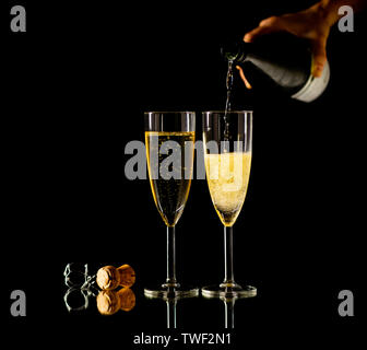 Zwei Gläser mit Champagner Ausgießen aus der Flasche bereit zu Toast in der Feier Konzept an Silvester Weihnachten Valentinstag und glückliche Zeiten isolieren Stockfoto