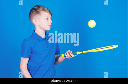 Träumen über Sport Karriere. Athlet kid Tennisschläger auf blauem Hintergrund. Tennis Sport und Unterhaltung. Junge Kind Tennis spielen. Tennis Fähigkeiten zu üben. Kerl mit Schläger genießen Spiel. Zukünftige Meister. Stockfoto