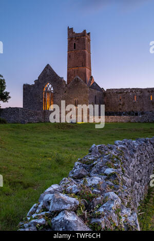 Ein Blick entlang einer Wand aus den Ruinen der mittelalterlichen Abtei Quinn Quinn, Irland gegen Deep Blue Sky, Porträt Aspekt Stockfoto