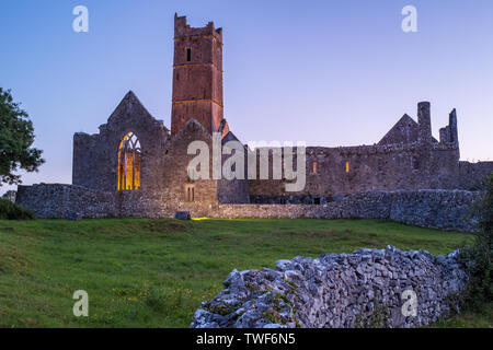 Ein Blick entlang einer Wand aus den Ruinen der mittelalterlichen Abtei Quinn Quinn, Irland gegen Deep Blue Sky. Stockfoto