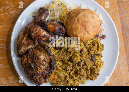 Die jamaikanische Essen. Traditionellen jamaikanischen Ziege, Jerk Chicken Curry und gebratene Knödel mit Reis und Erbsen. Stockfoto