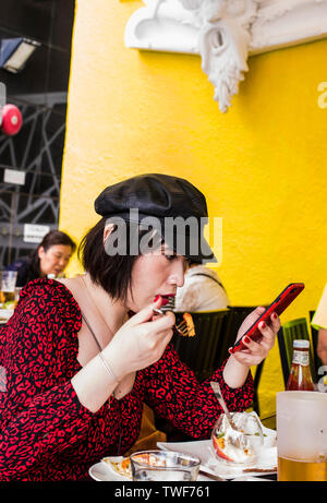 Frau sitzt im Cafe zu Mittag gegessen und Auf Smartphone in Stanley in Hongkong. Stockfoto