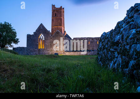 Eine niedrige Winkel Blick auf die Ruinen der mittelalterlichen Abtei Quinn Quinn, Irland gegen Deep Blue Sky, ländliche Wand im Vordergrund. Stockfoto