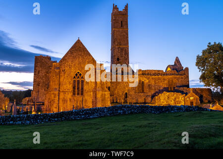 Blick auf die Ruinen der mittelalterlichen Abtei Quinn Quinn, Irland beleuchtet gegen deep blue sky, der Fußweg führt zum Stockfoto