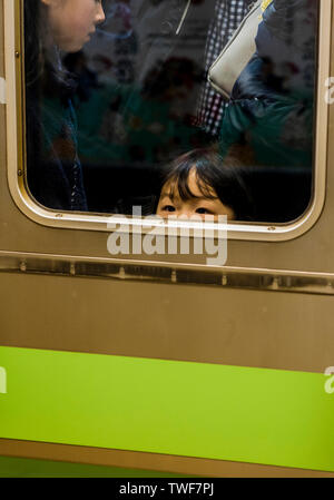 Junge Mädchen peering aus langen Zug Fenster in Tokio in Japan. Stockfoto
