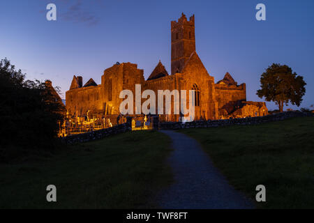 Die Ruinen der mittelalterlichen Abtei Quinn Quinn, Irland gegen eine deep blue sky Lit, Schuß, der Fußweg zur Abtei. Stockfoto