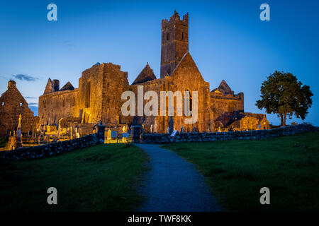 Die Ruinen der mittelalterlichen Abtei Quinn Quinn, Irland gegen eine deep blue sky Lit, Schuß, der Fußweg zur Abtei. Stockfoto