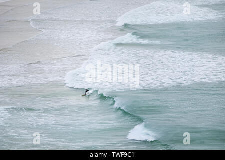 Ein einsamer Surfer auf einer Welle an Crantock Beach in Newquay in Cornwall. Stockfoto