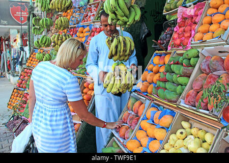 Frau Wahl Früchte im Fach aus. Frau touristische kaufen Früchte auf Straße Verkäufer. Mädchen kaufen, Mangos, Granatäpfel, Bananen, Pflaumen, Gua Stockfoto