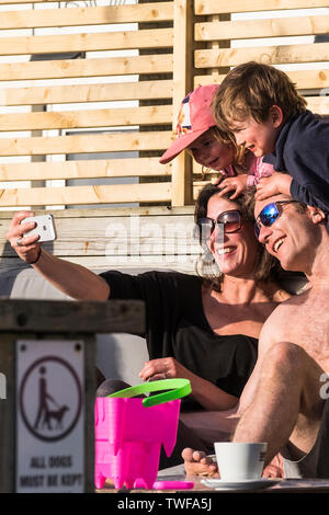 Eine glückliche Familie, der Urlauber ein selfie mit einem iPhone an einem sonnigen Fistral in Newquay in Cornwall. Stockfoto