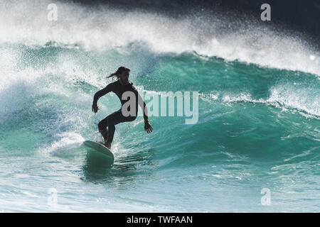 Spektakuläre surfen Aktion als Surfer reitet eine Welle im Jade farbigen Meer bei Fistral in Newquay in Cornwall. Stockfoto