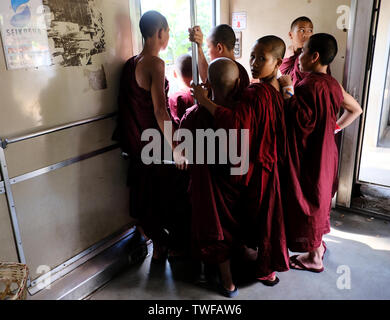 Junge buddhistische Mönche stehen in einem burmesischen Waggon in Yangon City. Stockfoto