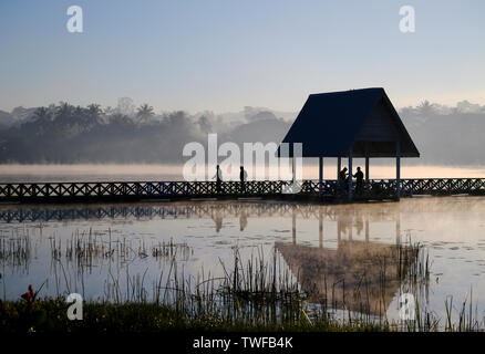 Die Zahlen sind Silhouette gegen Morgendämmerung Nebel an einem See in Loikaw in Myanmar steigt. Stockfoto